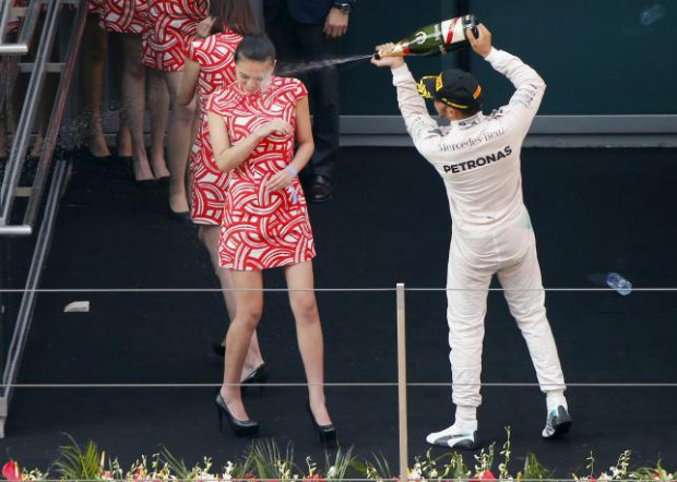 Mercedes Formula One driver Lewis Hamilton of Britain sprays champagne at a grid girl as he celebrates his victory on the podium after the Chinese F1 Grand Prix at the Shanghai International Circuit, April 12, 2015. REUTERS/Carlos Barria